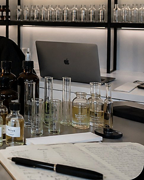 The Yevfumes studio bench, with test tubes, sample vials and formula notes laid out beside a laptop